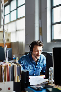 Businessman Wearing Headphones While Using Computer In Office