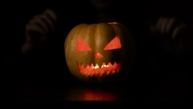 Isolated black background. The woman puts the pumpkin in the foreground. Halloween. Slowmotion