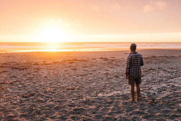 young male looking out at orange setting sun