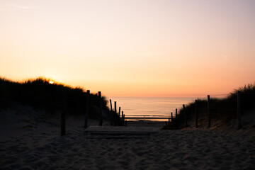 A sunset behind dunes by the sea