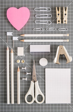 White office tools and pink notepad on grey background