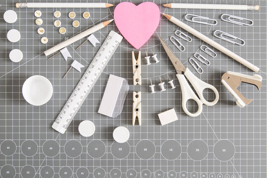 White office tools and pink notepad on grey background