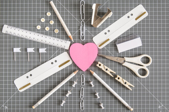 White office tools and pink notepad on grey background