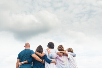 Upper body shot from the back of a family with their arms around each other