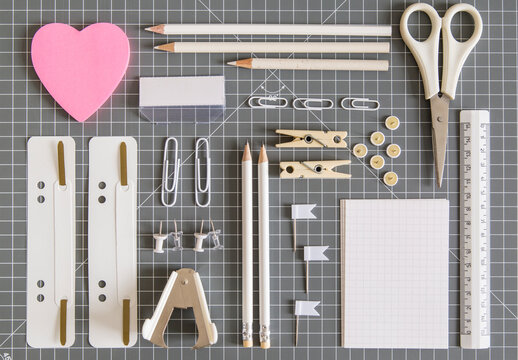 White office tools and pink notepad on grey background
