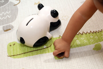 Child playing with brazilian real coin and panda safe