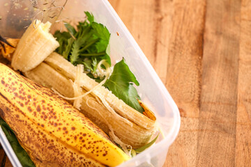 Container of fresh food scraps on wooden surface ready to be recycled into compost bin