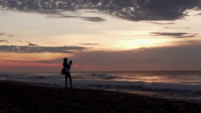 Woman take a beach sunrise picture