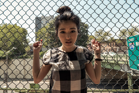 Pretty young woman holding on to a fence
