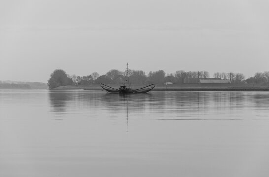 Old wooden fishing boat with two extension arms with trawling nets - black and white image
