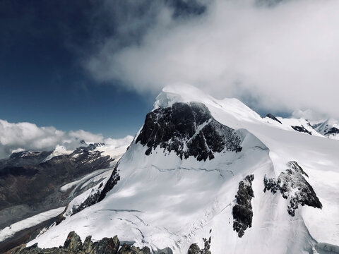 Snow-covered mountain peak with clouds coming in