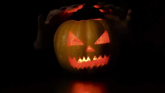 Young woman fooling around with a pumpkin. Halloween holiday. Isolated black background.