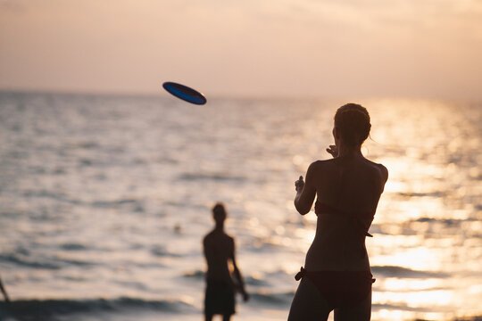 Friends on the beach playing frisbee