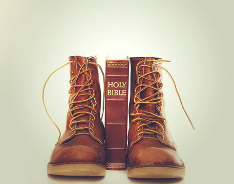 Bible and boots on gray background