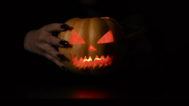 Isolated black background. The woman puts the pumpkin in the foreground. Halloween.