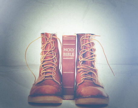 Bible and boots on gray background