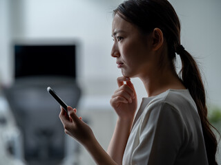 スマートフォンを見て考える女性