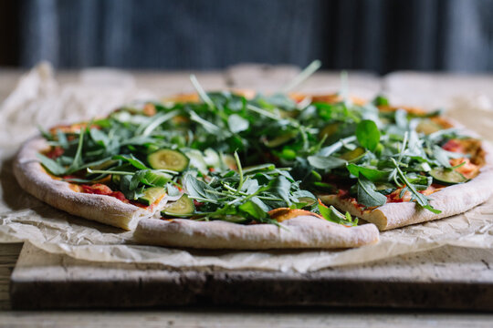Sliced italian pizza with courgette and arugula on wooden table - Powered by Adobe