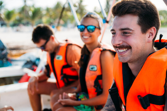 Group of happy friends with life jackets on a boat during their vacation