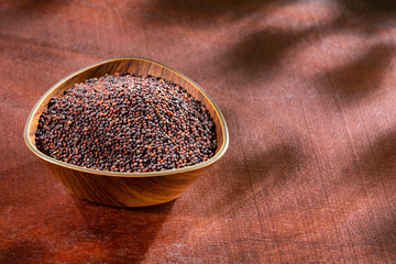 Brassica nigra - Black mustard seeds in wooden bowl