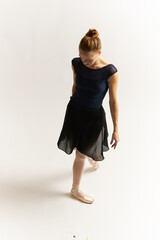 Ballerina in pointe shoes and in a tutu on a light background dance correct positioning of the legs slim figure 