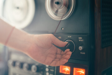 Female hand adjusting a knob on reel-to-reel tape recorder