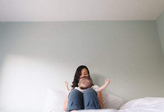 Young mom playing with baby inside - on bed
