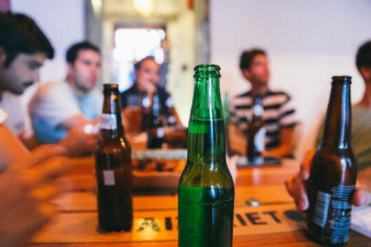 Bottle of beer on a table of a bar with friends watching sports match on TV