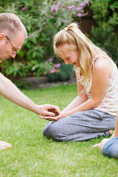 Girl laughing nervously as dad puts frog in her hand