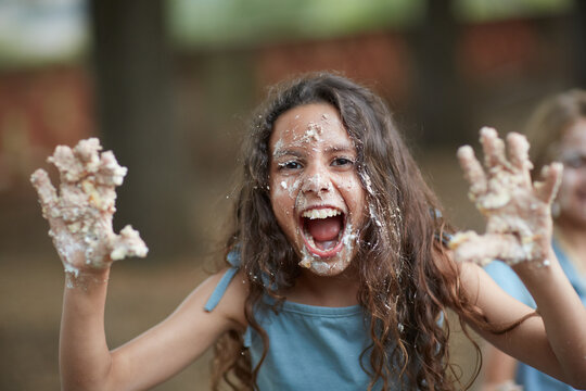 Funny young girl joking and playing with a birthday cake