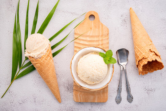 Coconut ice cream flavours in half of coconut setup on white stone background. Summer and Sweet menu concept.
