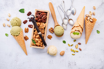 Pistachio and vanilla ice cream in cones  with mixed nut setup on white stone background . Summer and Sweet menu concept.