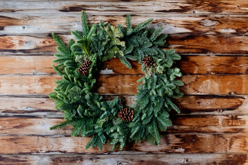 Simple evergreen wreath hangs on rustic wall