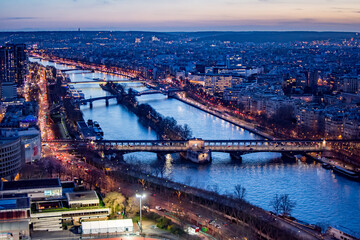 Fototapeta na wymiar Aerial view of the Seine River and cityscape in Paris France at dusk, with bridges and lights and sunset sky above the horizon