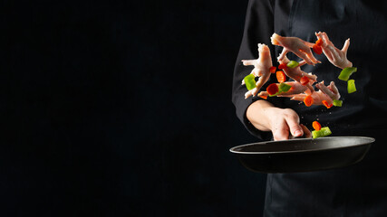 Close-up of chef holding frying pan with seafood and colorful mix of vegetables. Black background. Asian cuisine. Frozen motion. Food concept.