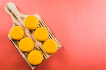 Delicious Quindins on wooden board, traditional Brazilian dessert made with egg yolk, sugar and coconut.