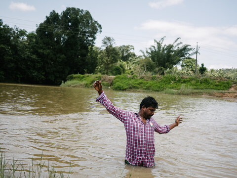Indian drunken man standing in dirty river