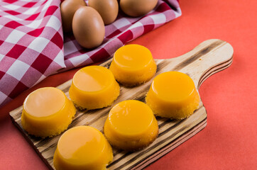Delicious Quindins on wooden board, traditional Brazilian dessert made with egg yolk, sugar and coconut.