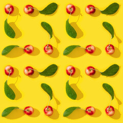 Seamless regular creative pattern from ripe small red apples and green leaves on yellow color background.