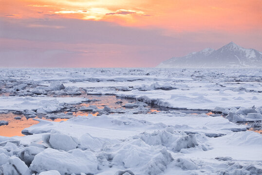 Landscape view of an orange sunset over ice floats in the Bering Sea in Alaska