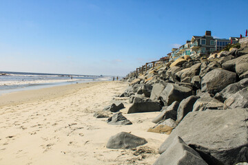 a gorgeous shot of the sandy beach and rocky hillsides, blue sky, beach front homes, clouds and...