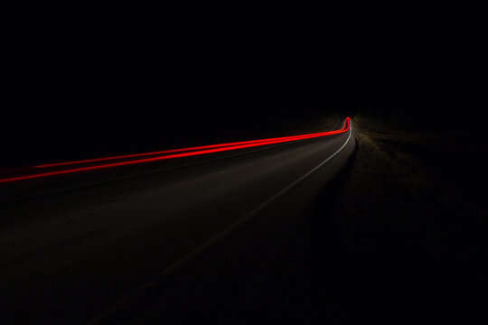 Red Taillight Trail Of Vehicle Driving On Road At Night