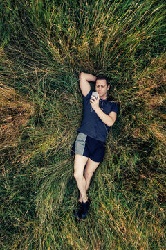 Runner PlaResting and Checking His Activity Tracker on the Phone 
