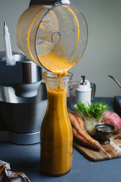 Freshly blitzed roasted sweet potato and fennel soup, being poured into a serving carafe.