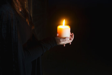 person holding lit candle in the dark