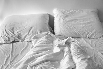 Grainy black and white of an unmade bed