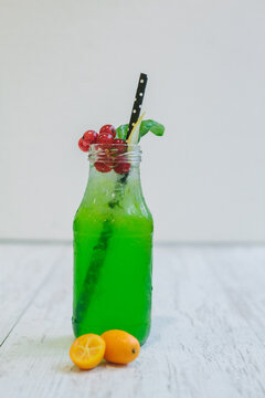 bilious green basil lemon cocktail with colorful fruit garnish