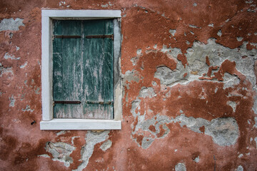 old window with cracked plaster and green wooden shutters