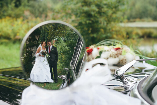 bridal couple seen in a rearview mirror from an classic oldtimer