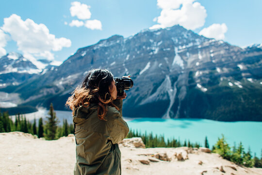 A woman ontop taking photographs of mountains